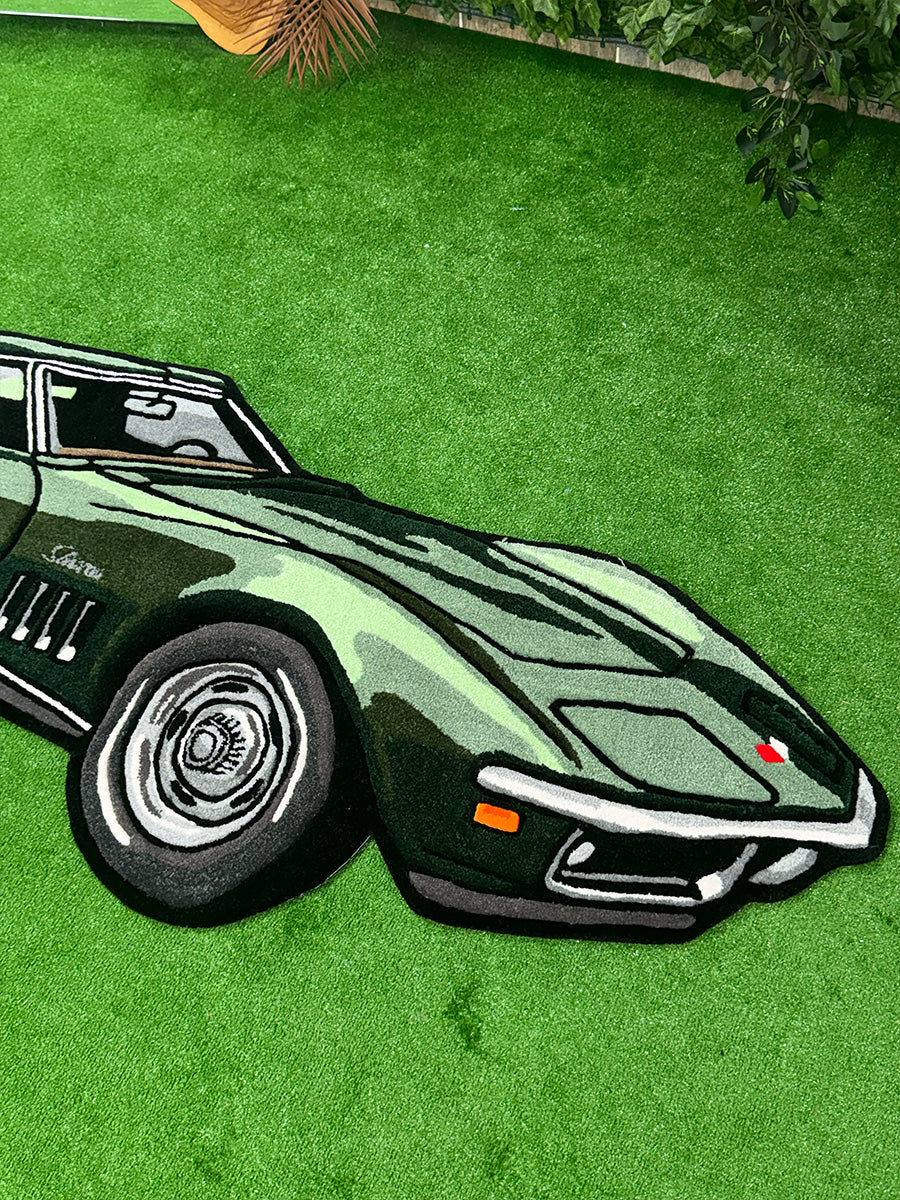 Zemin üzerinde sergilenen yeşil klasik araba tasarımlı tufting halı modelinin ön kaput ve karakteristik yan havalandırma (gill) detaylarının görünümü.