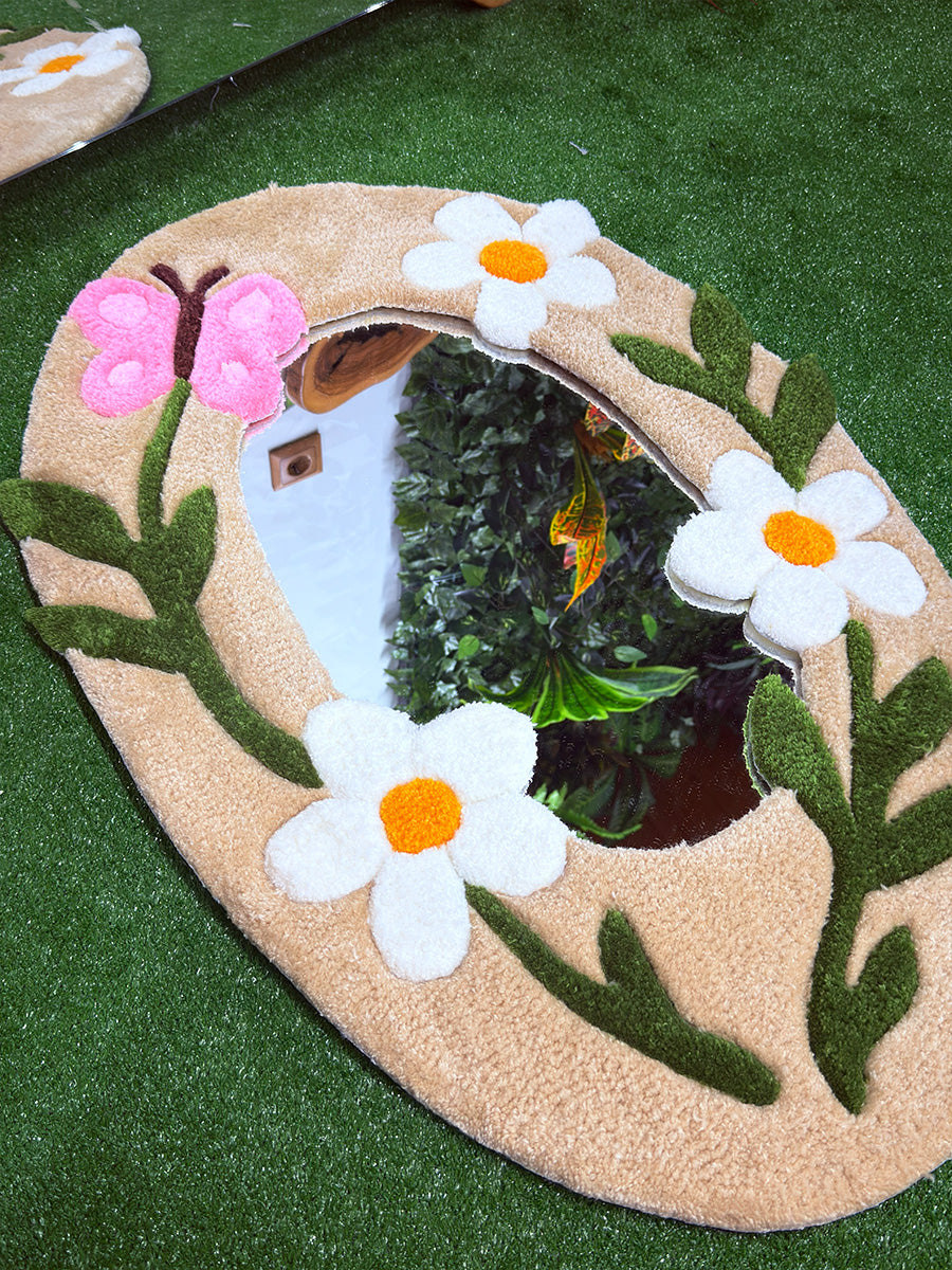 Yeşil zemin üzerinde dikey konumlandırılmış, 3D oyma tekniğiyle belirginleştirilen çiçek figürlü el yapımı tufting duvar halısı ayna tasarımı.