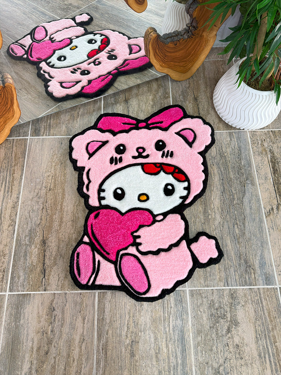 Sevimli pembe ayıcık şapkası ve göğsündeki parlak pembe kalbiyle tasarlanmış Hello Kitty Pink Edition el yapımı tufting halı; detaylı el işçiliği, dolgun iplik yapısı ve pürüzsüz yüzeyiyle dikkat çeken özel üretim dekoratif halı.