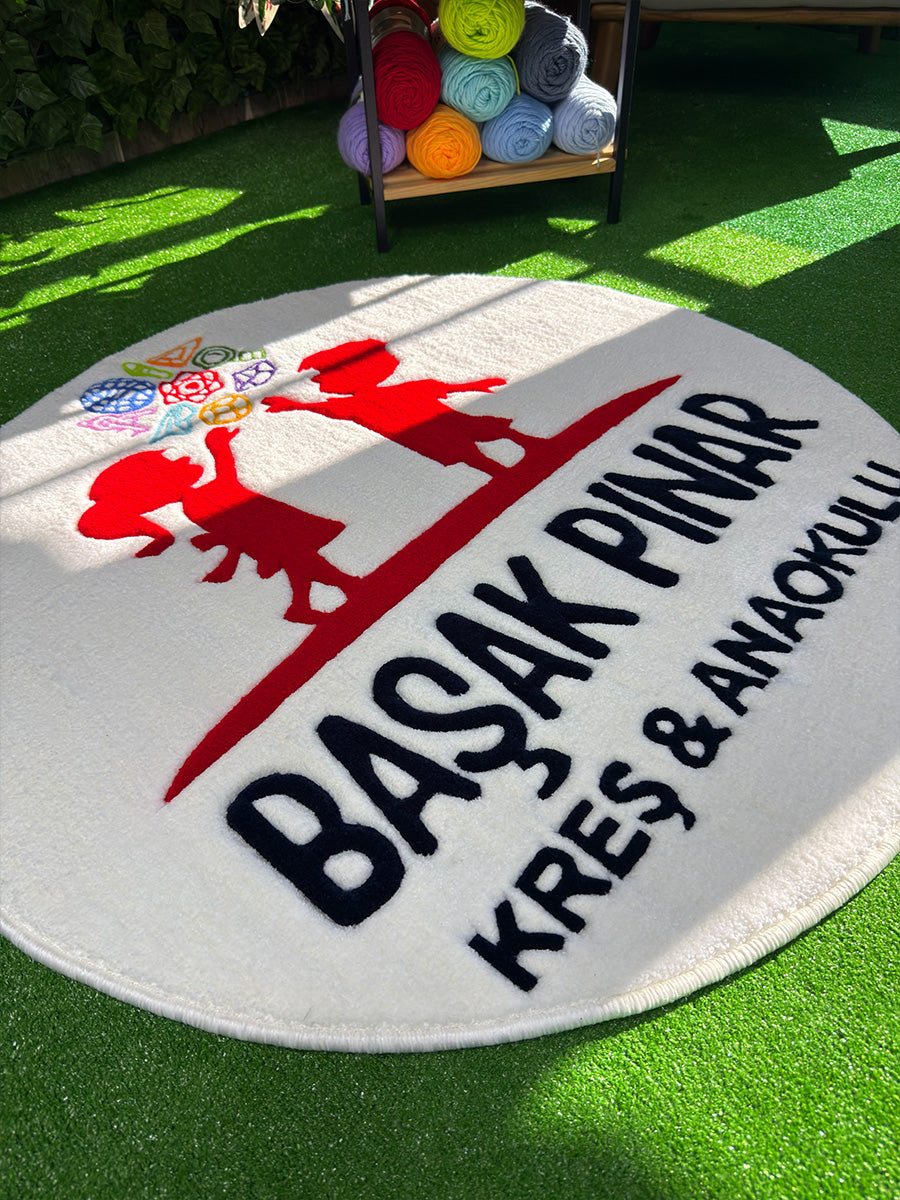 Logonun üst bölümündeki taç benzeri geometrik mavi ve kırmızı formların ilmek detaylarını yansıtan, el işçiliği tufting duvar halısı makro doku çekimi.