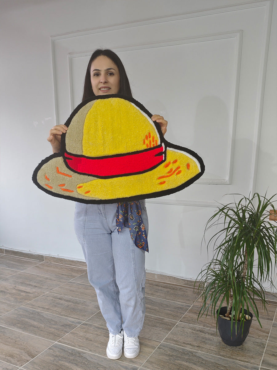 Kaliteli el işçiliğini ve 80x47 cm ebatlarındaki gerçek boyutunu net bir şekilde gösteren, yumuşak akrilik iplikten dokunmuş One Piece Luffy hasır şapka tufting halısı; dikkat çekici siyah dış hatları ve turuncu dikiş detaylarıyla öne çıkan, koleksiyonculara özel anime temalı tufting halı.
