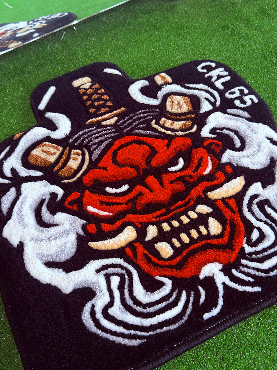 Kabartmalı 3D traşlama tekniğiyle kırmızı yüz hatlarına, sivri beyaz dişlere ve kıvrımlı duman desenlerine derinlik katılmış yakından görünüm tufting halı araba paspası tasarımı.