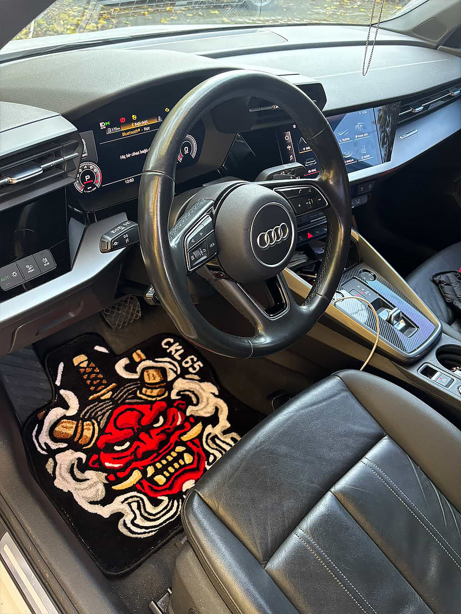 Siyah zemin üzerine işlenmiş kırmızı Japon Oni maskesi ve kılıç detaylarıyla öne çıkan, şoför mahalli zeminine birebir uyumlu özel kesim el yapımı tufting halı araç içi paspası.