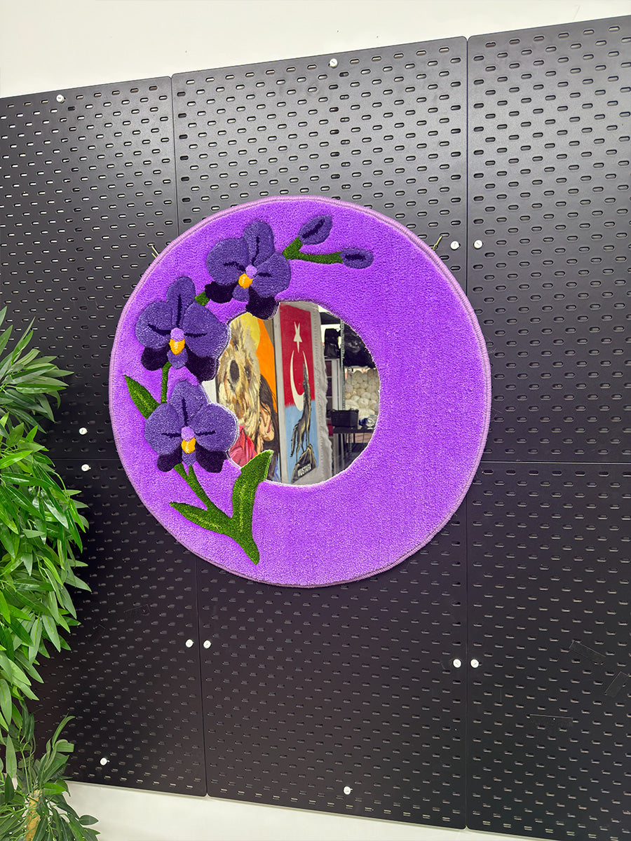 ORCHIS el yapımı tufting ayna modelinin siyah fon üzerinde tam karşıdan görünümü; lila zemin üzerine işlenmiş 3 boyutlu mor orkide detayları.