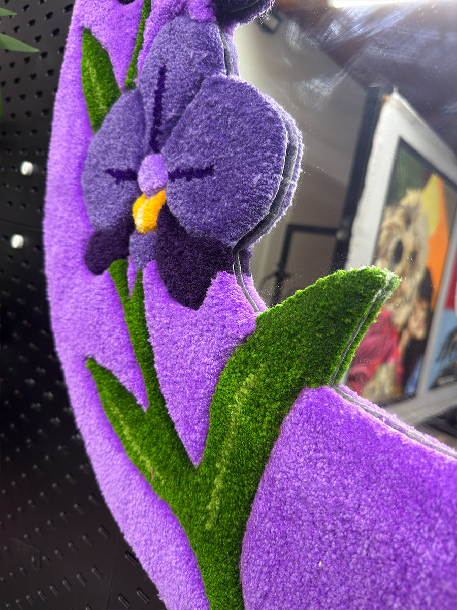 Dekoratif mor orkide aynada kullanılan yeşil dal ve yaprak figürlerinin makro çekimi; tufting sanatının el işçiliği ile sunulan boyutlandırma detayı.