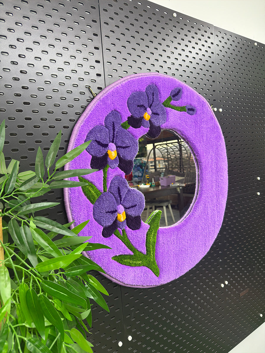 Duvara asılı mor orkide temalı tufting duvar aynasının perspektif görünümü; modern ev dekorasyonu için tasarlanmış el yapımı aynanın form yapısı.