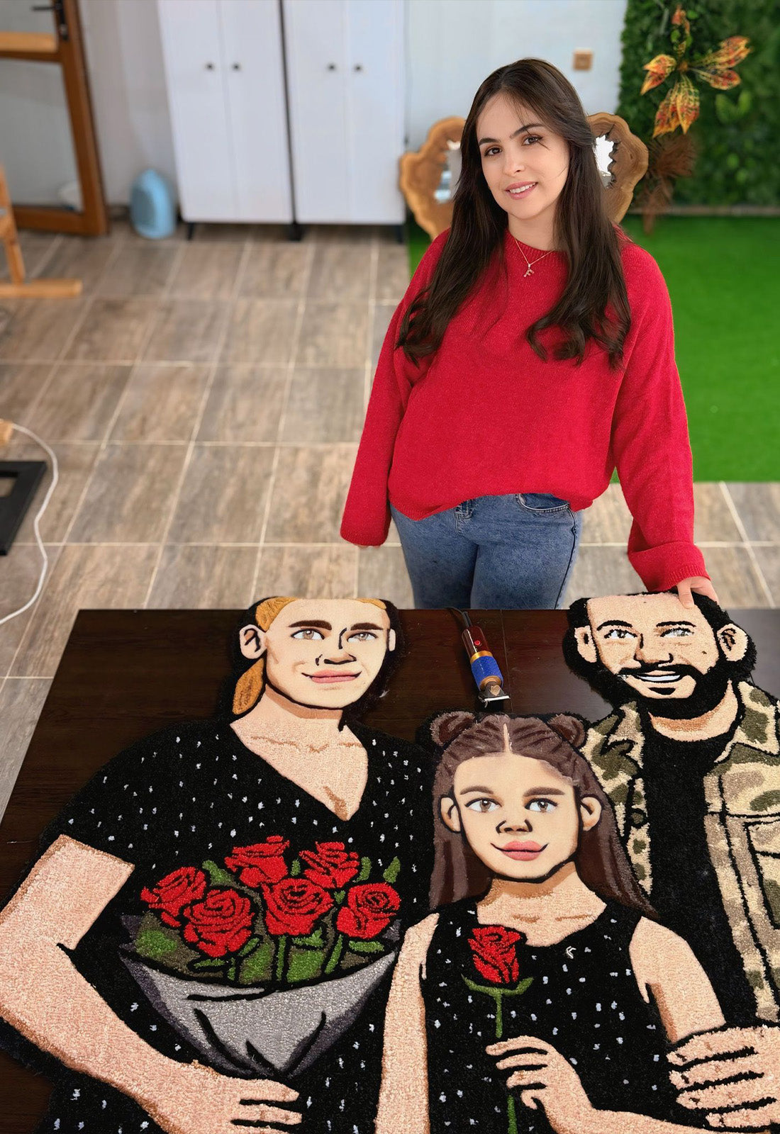 Kırmızı gül buketi tutan kadın, elinde tek bir kırmızı gül olan kız çocuğu ve kamuflaj desenli ceket giyen sakallı erkek figürünün detaylıca resmedildiği, siyah zeminli kişiye özel aile portresi tufting halı dokuması.